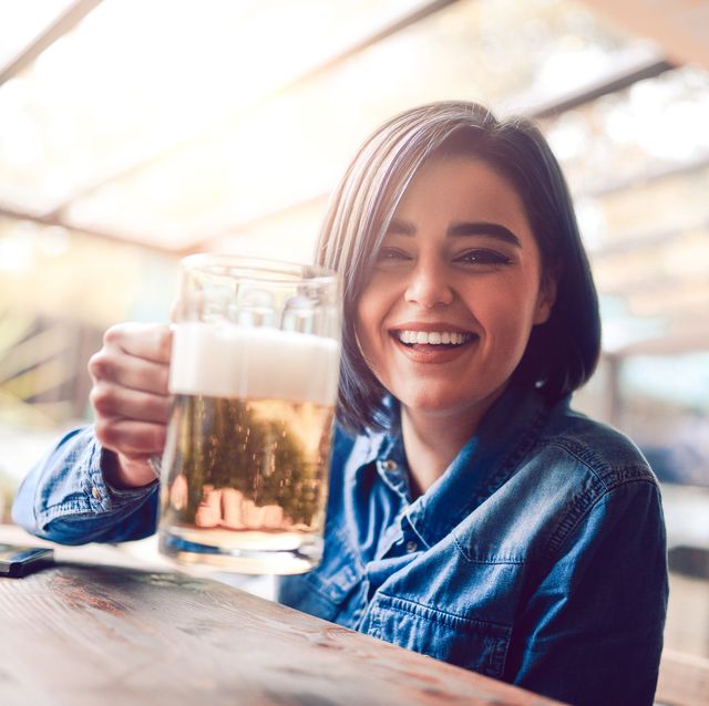 smiling female drinking beer in city pub on a sunny day