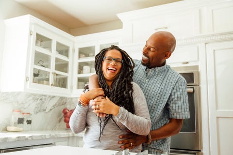 smiling man embracing female partner in kitchen at home smiling man embracing female partner in kitchen at home