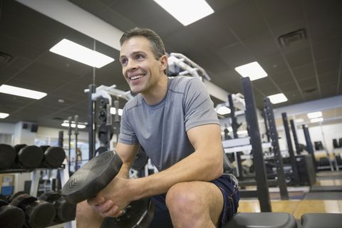 Smiling man weight lifting at gym