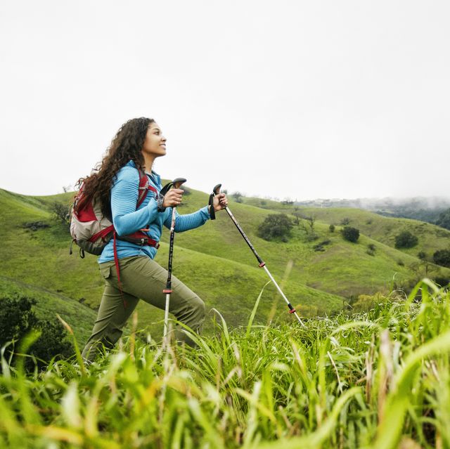 smiling mixed race woman hiking with walking sticks