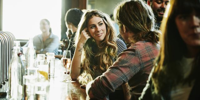 smiling woman flirting with man while sitting in bar