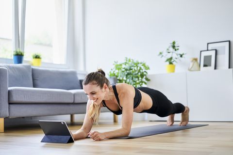 smiling woman learning plank exercise on internet at home