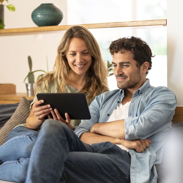 smiling woman with boyfriend looking at digital tablet at home