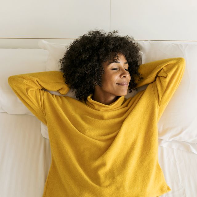 smiling woman with closed eyes lying on bed