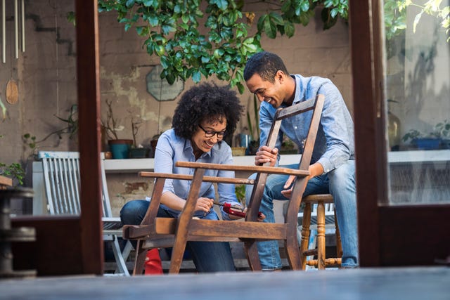 smiling young couple working together to restore a chair