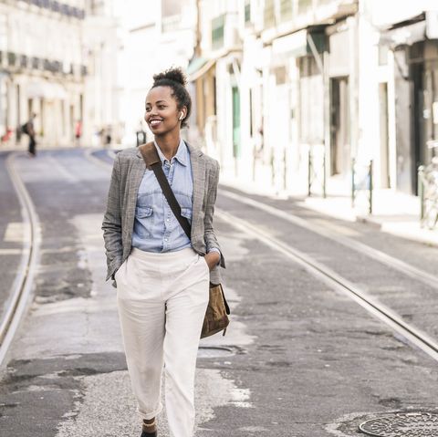 smiling young woman with wireless earphones in the city on the go, lissabon, portugal