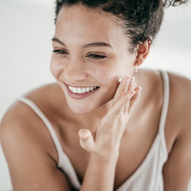 smiling young women applying moisturiser to her face