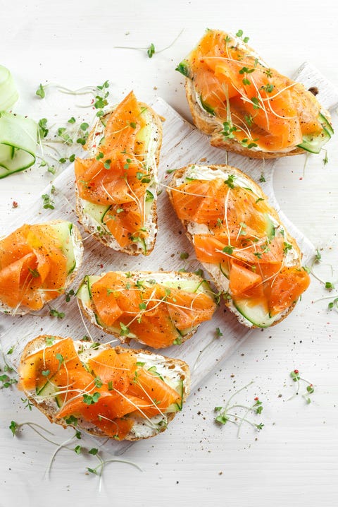 Smoked salmon bruschettas with soft cheese and cucumber shavings on white board. Smoked salmon bruschettas with soft cheese and cucumber shavings on white board.