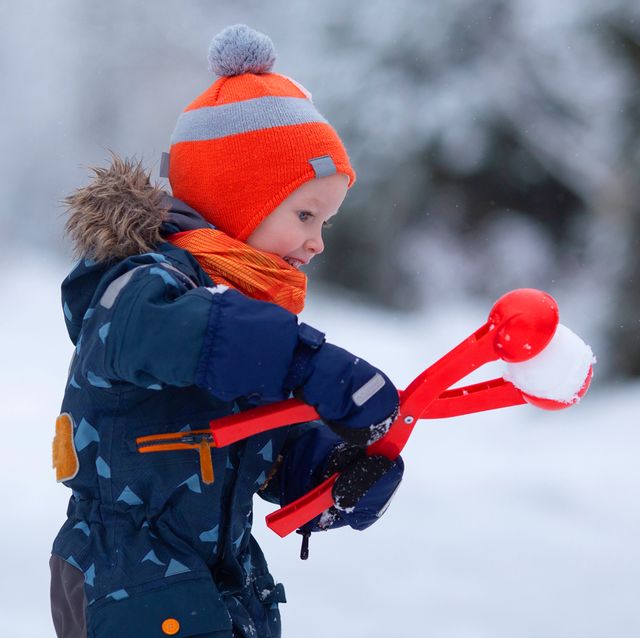 little kid playing with snow ball maker outside