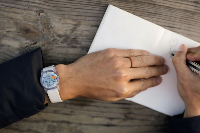a person holding a pen and a paper wearing a watch