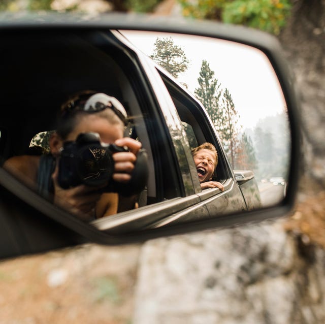 son screaming while mother photographing with camera reflecting on side view mirror