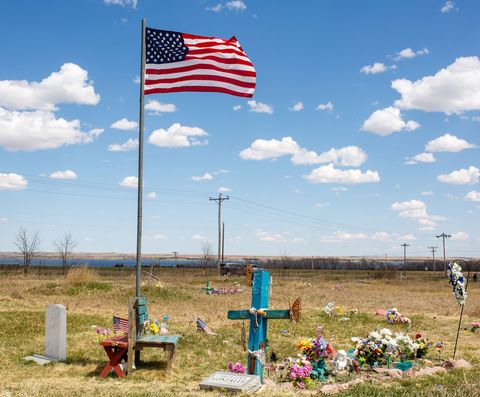 a us flag flies near a grave at the lower brule indian reservation on april 22, 2020 in lower brule, south dakota   the threat posed by the novel coronavirus to particularly vulnerable populations has cast a shadow over the daily reality, already filled with difficulties, of sioux tribe members photo by kerem yucel  afp photo by kerem yucelafp via getty images