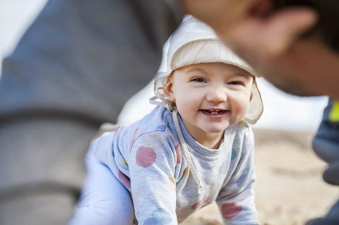 Spain, Lanzarote, portrait of laughing baby girl playing with father on the beach