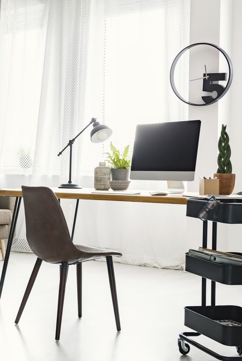 home office interior with sofa, graphics, desk with a computer and lamp and modern clock