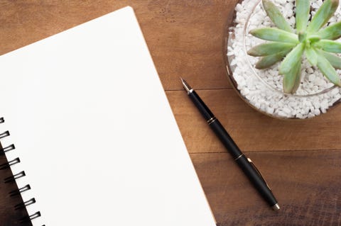 Spiral notebook, fountain pen and vase on the table