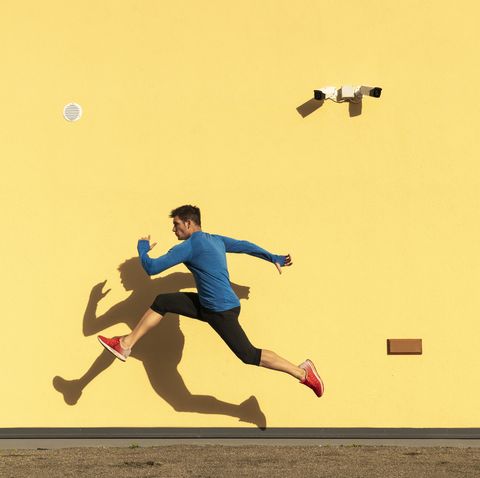 sportive man exercising at yellow wall with cctv camera