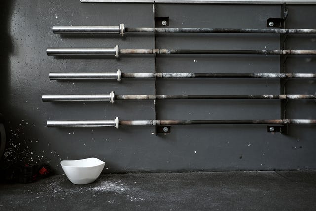 sports chalk bowl under a collection of barbells on a rack