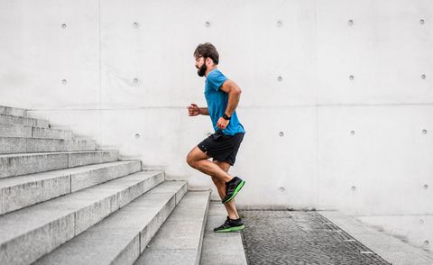 sporty man running up steps in urban setting