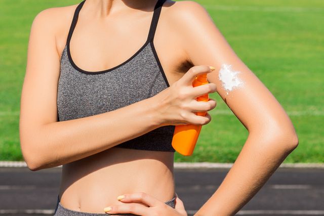 sporty woman applying sunscreen on sport area before run