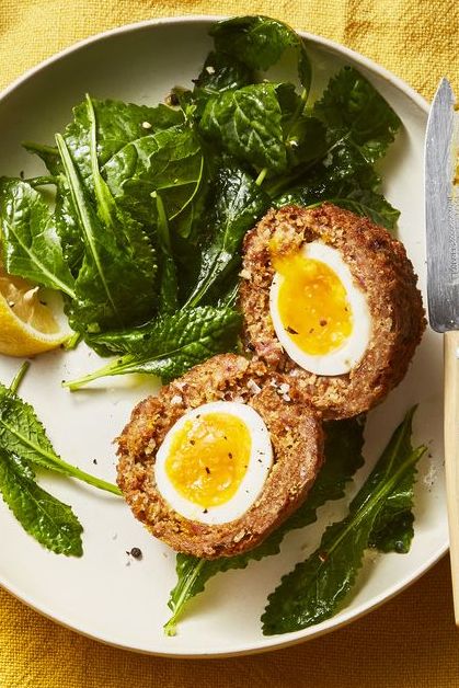 scotch eggs with salad on a white plate
