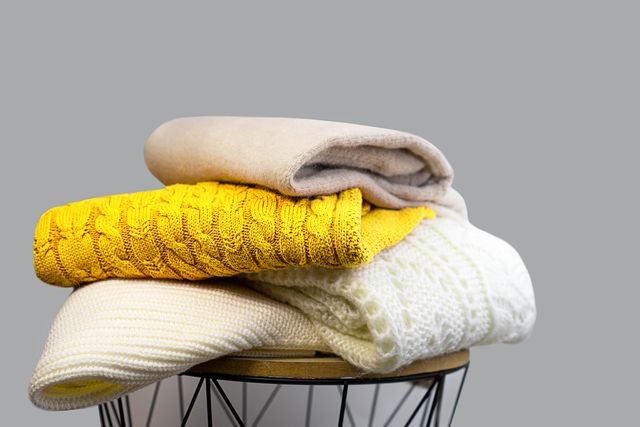stack of trendy bright illuminating yellow, gray and white woolen knitted sweaters