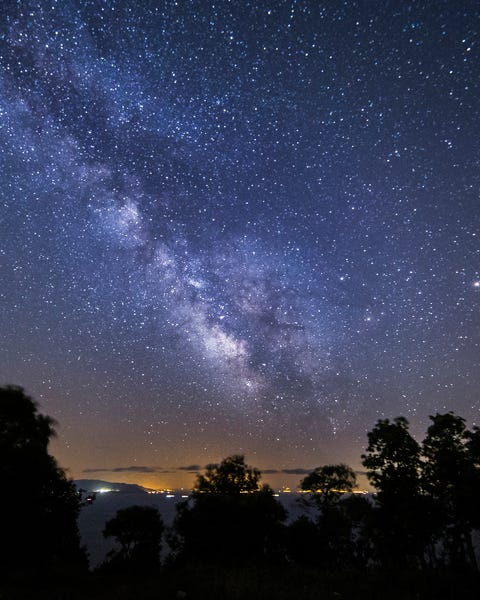 milky way near the sea, city lights adds sunset effect