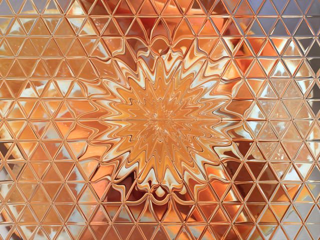 full frame shot of a metallic surface with triangle shape mosaic reflecting some oranges