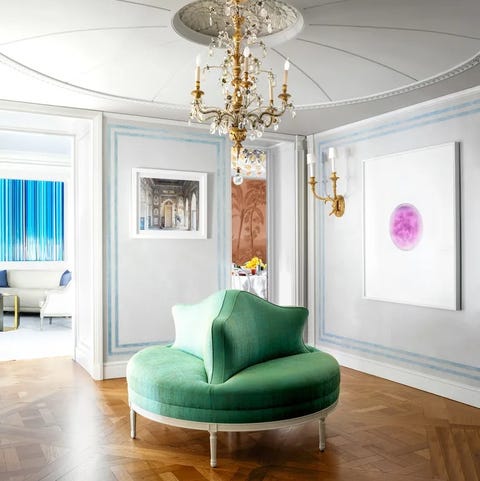 green circular banquette with triangular seatback in center in a room with marquety floors and artwork on the walls