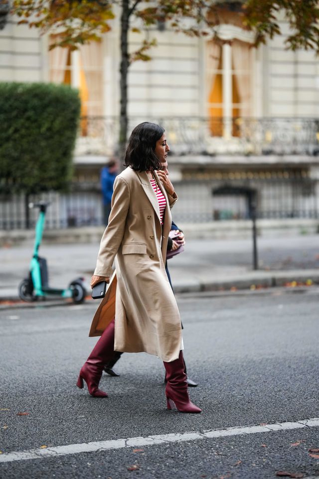 paris, france   september 26 a guest wears a red and white striped print pattern t shirt, a beige long coat, a white wrap knees skirt, red shiny leather pointed heels knees boots, a brown shiny leather belt , outside jacquemus, during paris fashion week   womenswear springsummer 2023 on september 26, 2022 in paris, france photo by edward berthelotgetty images