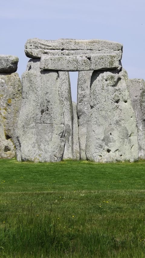 Stonehenge On Grassy Field Against Sky