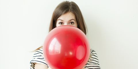 Studio shot of young woman blowing balloon