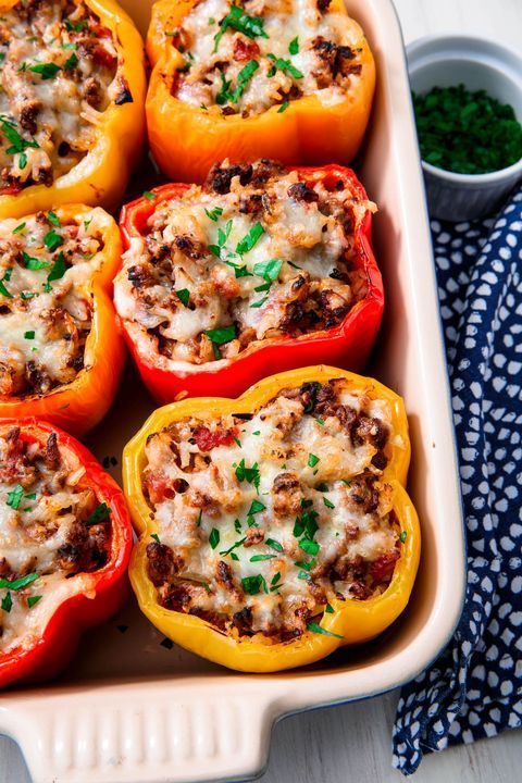 red and yellow peppers stuffed with ground beef and cheese in a white baking dish