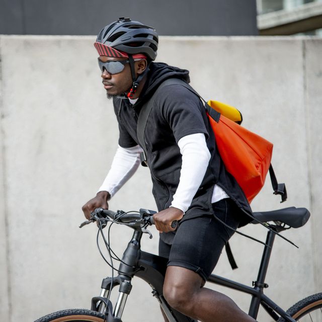 Stylish young man with a messenger bag riding a bicycle in the city.
