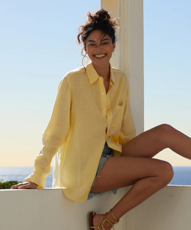 woman smiling in yellow shirt in front of the beach