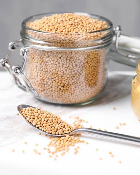 mustard seeds on white marble table spoon