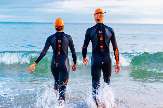 two people wearing sumarpo wetsuits going into the ocean