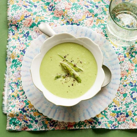 cream of asparagus soup in white bowl with asparagus tips