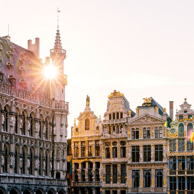 sun shining through historic buildings at grand place in brussels, belgium