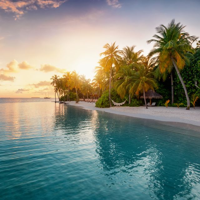 sunrise behind a tropical island in the maldives