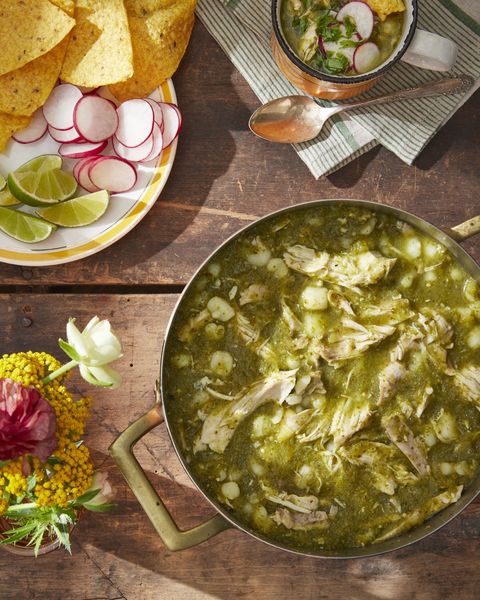 chicken pozole verde with cilantro chimichurri in a dutch oven with a plate of toppings next to it