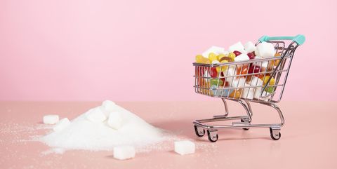supermarket trolley with candy next to pile of sugar
