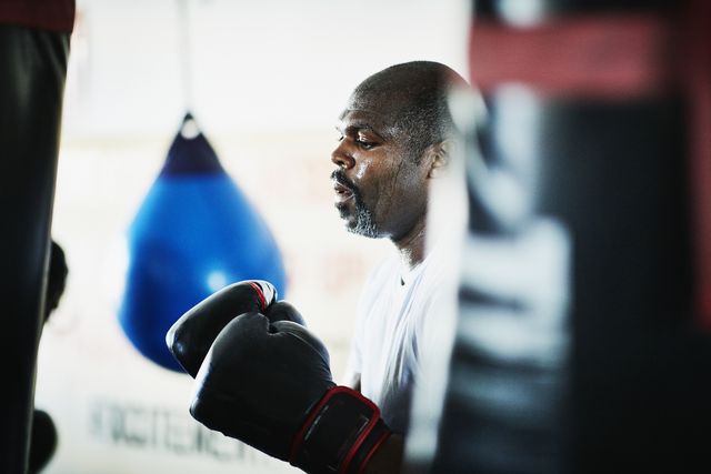 sweating male boxer working out on heavy bag in boxing gym