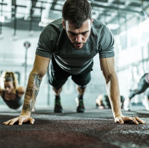 Sweaty athletic man exercising push-ups on cross fit training in a gym.