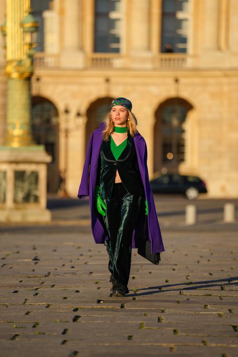 paris, france   november 23 almuneda lapique wears a green with purple shell print pattern silk scarf as a headband from hermes, gold and pearls earrings, a green ribbed turtleneck  cut out chest  cropped t shirt, a dark green shiny velvet blazer jacket from gucci, matching dark green shiny velvet large suit pants from gucci, neon green shiny leather gloves, a black shiny leather with ysl silver buckle handbag from yves saint laurent, a neon purple long wool coat from zara, black sneakers, during a street style fashion photo session, on november 23, 2021 in paris, france photo by edward berthelotgetty images