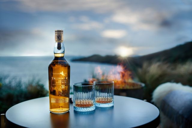 a bottle of talisker 30 year old single malt scotch whisky and glasses by the ocean