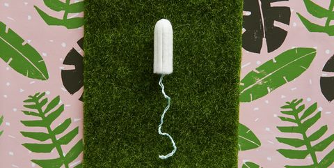 Tampon lying on fake grass against tropical background