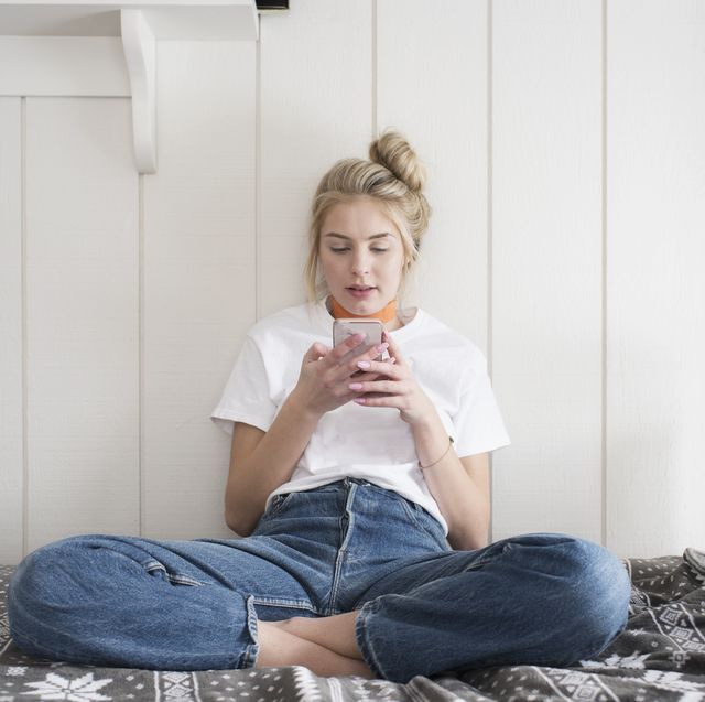 teen girl with phone sitting on bed