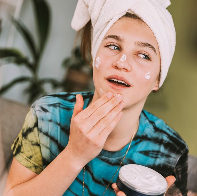 teenager applying skincare to face