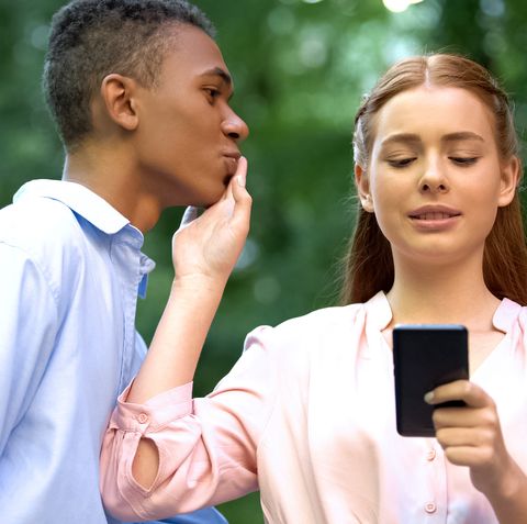 teenage girl chatting smartphone rejecting mixed race boyfriend kiss, addiction