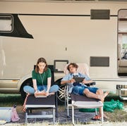Teenage siblings watching movie on digital tablet while sitting on folding chairs against motor home at campsite teenage siblings watching movie on digital tablet while sitting on folding chairs against motor home at campsite